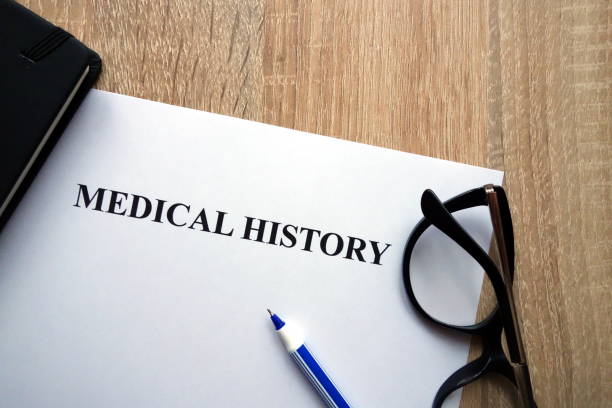 Medical history document, pen and glasses on desk Medical history document, pen and glasses on desk